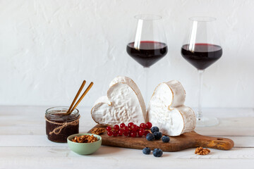 Heart shape cheese served with berries and two red wine glasses, Valentine Day concept