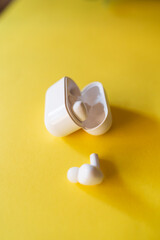 Top down view of wireless earbuds headphone on the yellow background