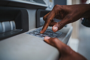 Close up shot of a man typing his PIN code on a keyboard of a ATM to withdrawal money from bank