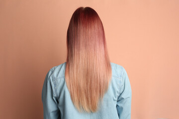 Woman with bright dyed hair on pale pink background, back view
