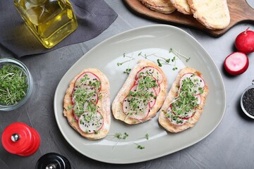 Delicious sandwiches with radish, cheese and microgreens on grey table, flat lay