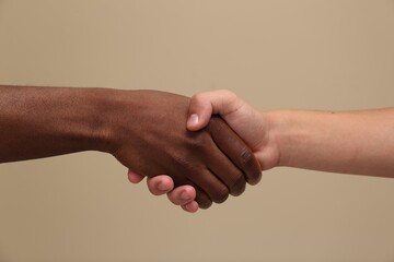 Men shaking hands on beige background, closeup