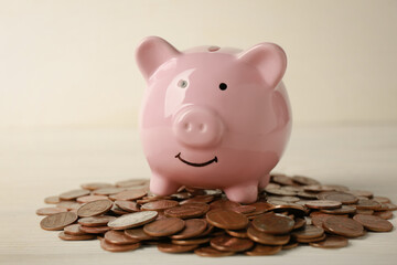 Ceramic piggy bank and coins on white wooden table, closeup