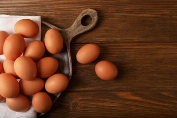 Raw brown chicken eggs on wooden table, flat lay. Space for text