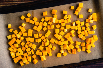 Diced Butternut Squash Tossed in Olive Oil on a Sheet Pan: Cubes of seasoned winter squash on a...