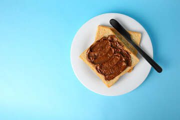 Tasty toast with chocolate paste on light blue background, top view. Space for text