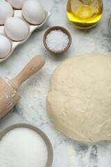 Fresh yeast dough and ingredients on white marble table, flat lay