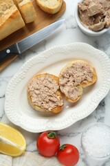 Tasty sandwiches with cod liver on white marble table, flat lay