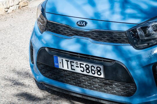 Photo of a bright blue, small KIA car with Greek license plate parked in the charming fishing village of Naoussa. Small cars like these are popular or rental cars for exploring the Greek islands.