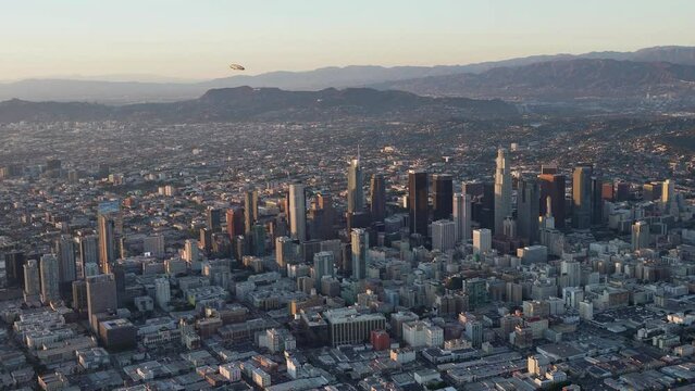 Aerial view of Downtown Los Angeles with the Goodyear Blimp overhead and Griffith Park with Hollywood Sign and Griffith Observatory in the background