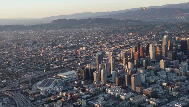 Aerial view of Downtown Los Angeles with Goodyear Blimp overhead and Griffith Park, Griffith Observatory, and Hollywood Sign in the background