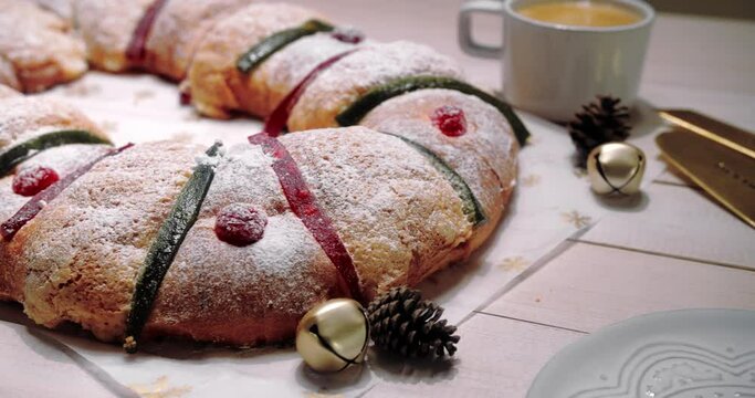 Panning beauty shot of Traditional Mexican bread for Day of the Kings, called "Rosca de Reyes Magos". With coffee on the side and Christmas elements. Epiphany bread.