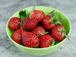 Strawberries in a green bowl on a gray stone background