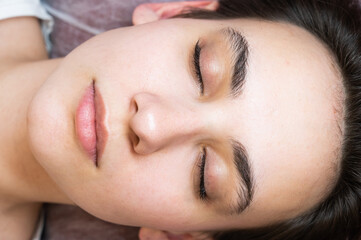 Woman lying on the couch after eyelash lamination procedure. 