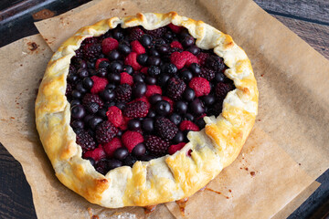 Freshly Baked Mixed Berry Galette on a Parchment-Lined Sheet Pan: Rustic dessert tart made with raspberries, blueberries, and blackberries