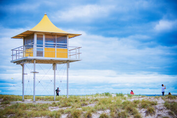 bright yellow lifeguard tower on the beach with sky and cloud