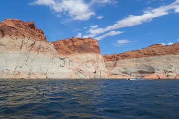 Fototapeta na wymiar Boat on the Colorado River at Glen Canyon National Recreation Area with colorful sandstone formation in background