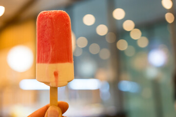 Holding a pink strawberry ice lollies. Close up