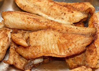 Baked tilapia filet in a steel serving pan