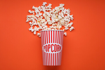 Bucket of tasty popcorn on orange background, flat lay