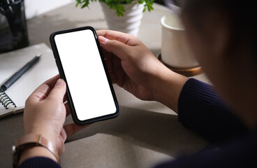 Close up view woman holding mobile phone at workspace.  Blank screen for your advertise design.
