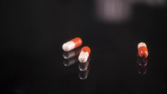 The man drops pills from his hand, enzyme, pancreatic treatment. Close-up shot on a black surface. Scene A.