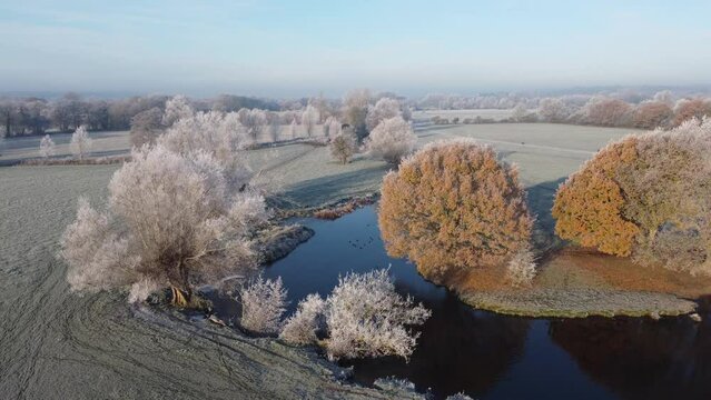 Aerial footage of a hoar frost over trees along the river stour early morning.