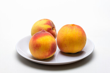 ripe peaches in a shallow dish, on a white milky background.