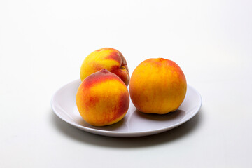 Fototapeta na wymiar ripe peaches in a shallow dish, on a white milky background.