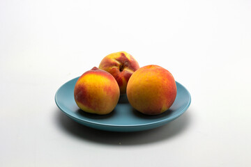 ripe peaches in a shallow dish, on a white milky background.