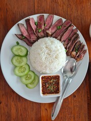 many pieces of beef on a plate  rice with sauce  Make cucumbers look appetizing.