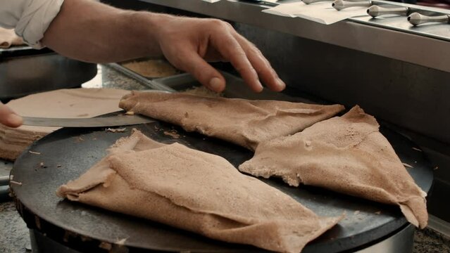 Close up of a person making delicious crepes in slow motion. French sweet cuisine.