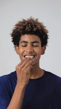 a handsome teenager afro smiling looking to the camera and putting on dental aligners wearing a blue t-shirt