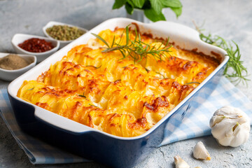 Potato gratin - graten (baked potatoes with cream and cheese) with rosemary and forks (Turkish name; Kremali patates)