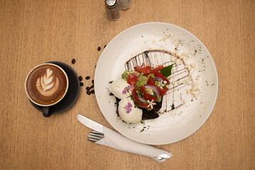 Breakfast or brunch plate of rye sourdough bread,smashed avocado with lemon oil, tomatoes and two poached eggs decorated with editable flowers and a cappuccino cup on the side
