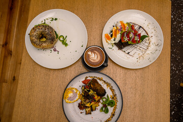 Top view of three plates with different types and portions of breakfast on the table