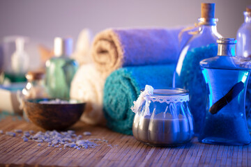 Spa and wellness concept. Bottles with bath and spa cosmetics, rolled up towels, bath salts and care products on wooden rustic paneling.
