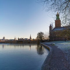 Pier at the canal Karbergskanalen, resting bench and the Town City Hall in background, a low winter...