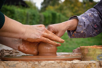 Pottery training. Two pairs of female hands over a potter's wheel in liquid clay. Harmonious contact between master and student