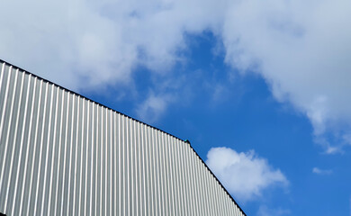 Fototapeta na wymiar metal roof panel with blue sky and white clouds in the background.