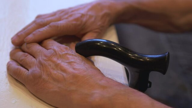 close-up of an old man's hand on a walking stick table, selective focus. a pensioner sits at an empty table. the need for old age. a pensioner in anticipation, depression, loneliness