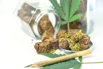 Dried marijuana in a jar with green marijuana leaves and rolls on a white background. Medical marijuana dispensary Alternative medicine Cannabis plantation for medical and business concept.