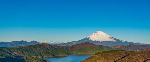 Panoramic view of Mt. Fuji and Lake Ashinoko with blue sky background.