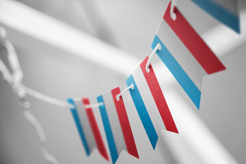 A garland of Luxembourg national flags on an abstract blurred background