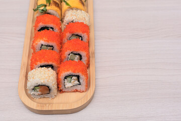 Delicious Japanese rolls with salmon, avocado, cucumber, cheese on wooden plate with selective focus. Asian food concept. Healthy eating