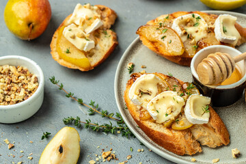Pear and brie crostini with honey, walnut and thyme, New Years Eve or Christmas party appetizer. banner, menu, recipe place for text, top view