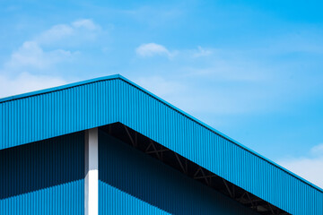 Blue corrugated steel roof with awning of warehouse building against blue sky background