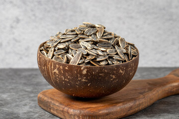 Shelled sunflower seeds on dark background. Salted sunflower seeds in a coconut bowl. close up