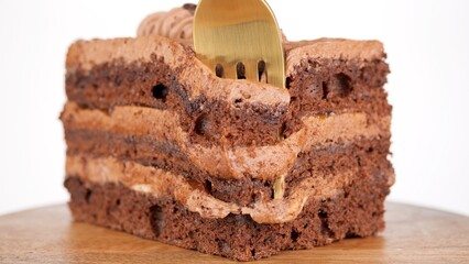 Eating chocolate dessert with golden fork. Take a slice chocolate biscuit cake 
