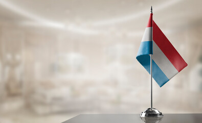 A small Luxembourg flag on an abstract blurry background - obrazy, fototapety, plakaty